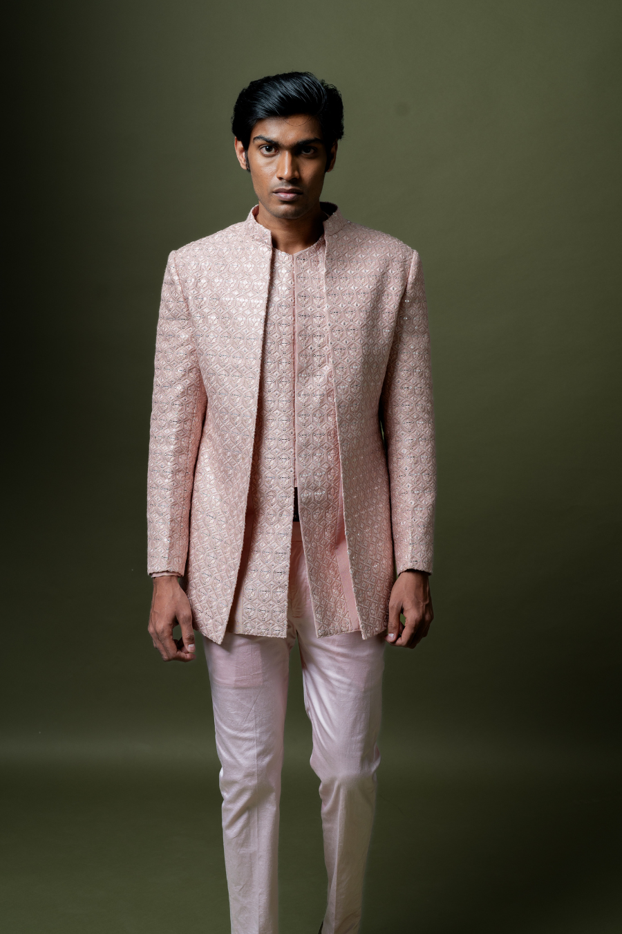 Man wearing a blush pink embroidered Jodhpuri suit set with matching trousers, styled for South Indian weddings and traditional ceremonies.
