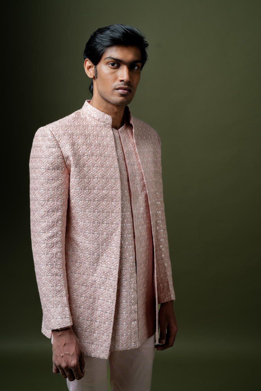 Man wearing a blush pink Jodhpuri suit with detailed embroidery, styled for South Indian engagement or reception functions.