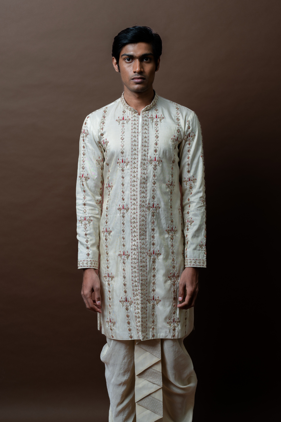 Gracefully tailored with refined embroidery, this ivory kurta and pleated dhoti set is an exquisite choice for South Indian grooms on their wedding day, engagement, or Muhurtham ceremony.