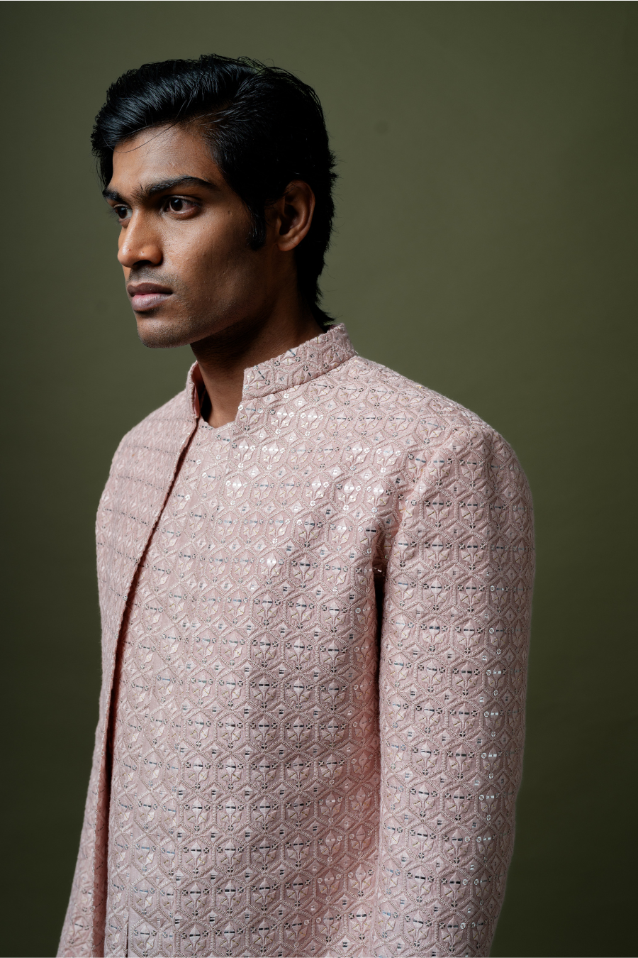 Full-length image of a man in a hand-embroidered blush pink Jodhpuri suit, best suited for Hyderabad weddings.