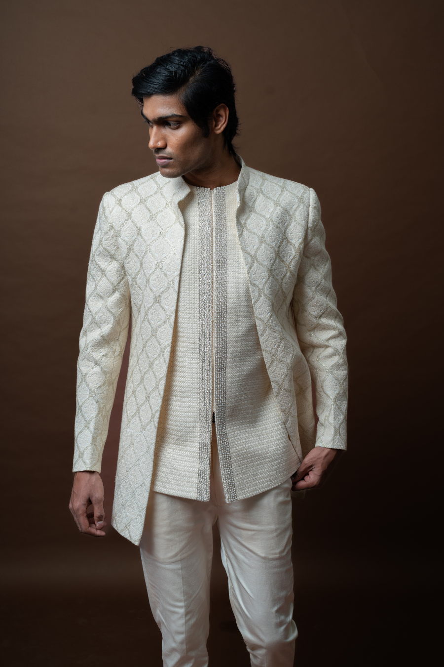 Ivory Jodhpuri suit featuring delicate patterns, modeled by a man for traditional wedding occasions.