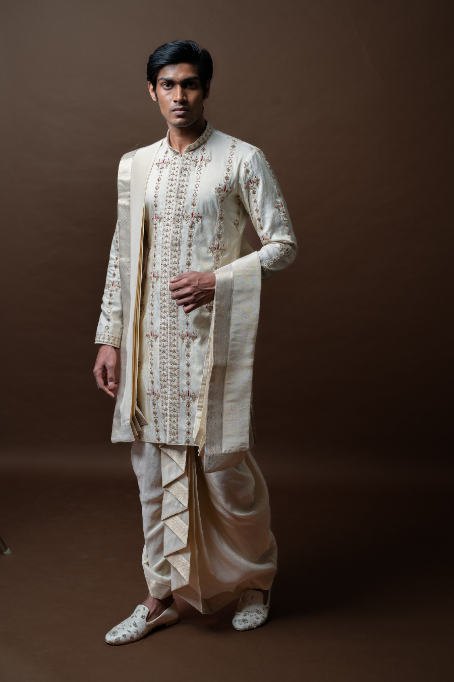 A timeless classic for the modern groom, this ivory kurta dhoti ensemble features floral motifs and an elegant dupatta, making it ideal for Pellikoduku and wedding festivities in Hyderabad.