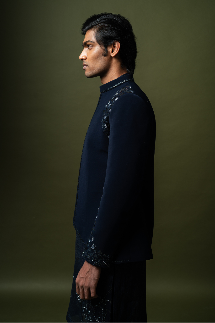 High-end navy blue Jodhpuri suit modeled by male seated on stool, designed for South Indian grooms.