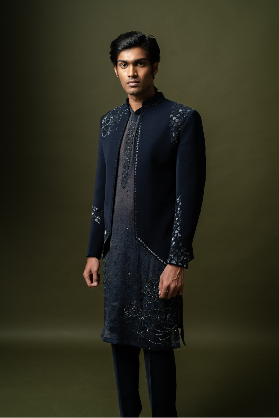 Seated groom in navy Jodhpuri outfit with minimal shimmer work, ideal for reception or pellikoduku event.