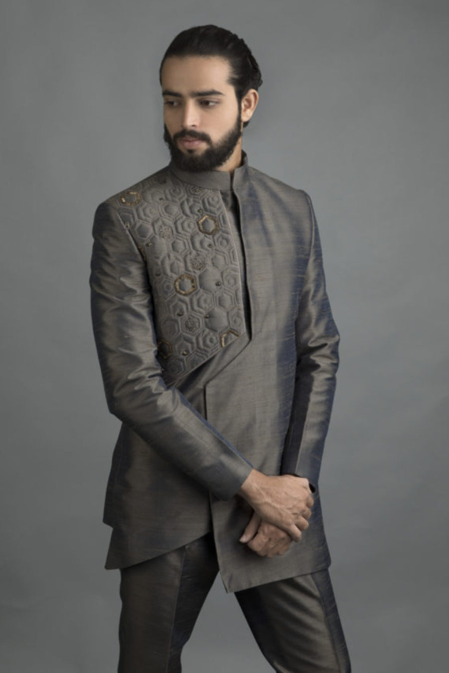 Groom in stone grey Indo-Western with asymmetrical hexagon embroidery and metallic accents, ideal for modern wedding events in Hyderabad.