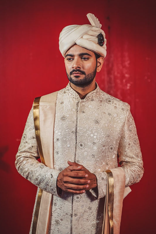 South Indian groom dressed in ivory hand-embroidered Pattu Sherwani with gold border dupatta and traditional turban, perfect for wedding, Muhurtham, and Pellikoduku ceremonies in Hyderabad.