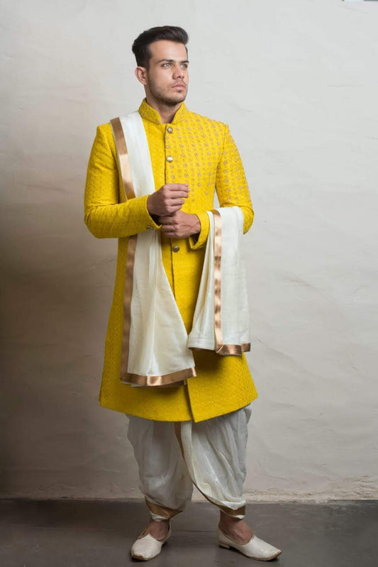 South Indian groom wearing vibrant yellow hand-embroidered Pattu Sherwani with white dhoti and gold border dupatta, perfect for wedding, Muhurtham, and Pellikoduku ceremonies in Hyderabad.

